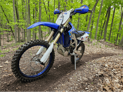 Blue Yamaha dirt bike parked in the woods