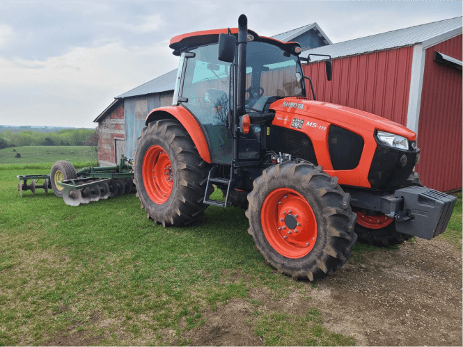 Orange Kubota tractor with disc harrow attachment