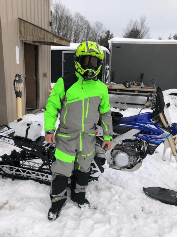 Dave Mann in hi-vis snowmobile gear standing next to snowmobiles